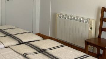 Un dormitorio con una cama, un radiador, una puerta y un cuadro en la pared.