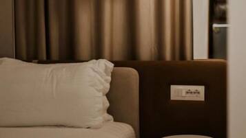A hotel room with a bed, a small round table, and a hanging pendant light.