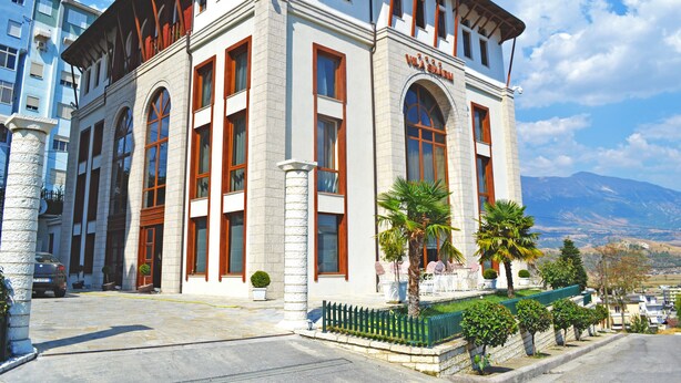 A white building with arched windows and a stone facade. - Sharm Hotel (Gjirokastër)