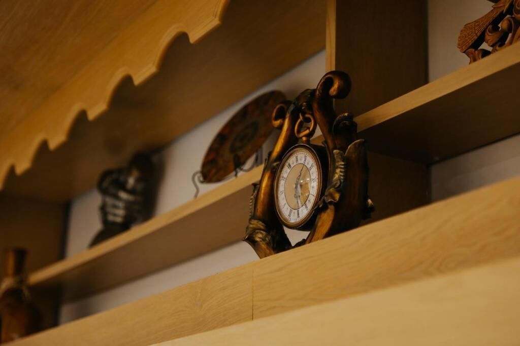 A wooden shelf with a clock and a decorative item.