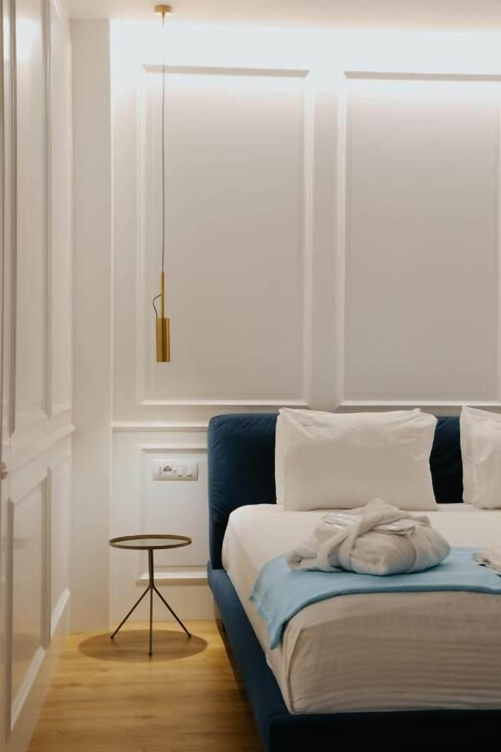 A bedroom with a bed, bedside table, and a hanging light fixture.