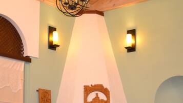 A room with a fireplace, wooden mantel, and wall sconces.