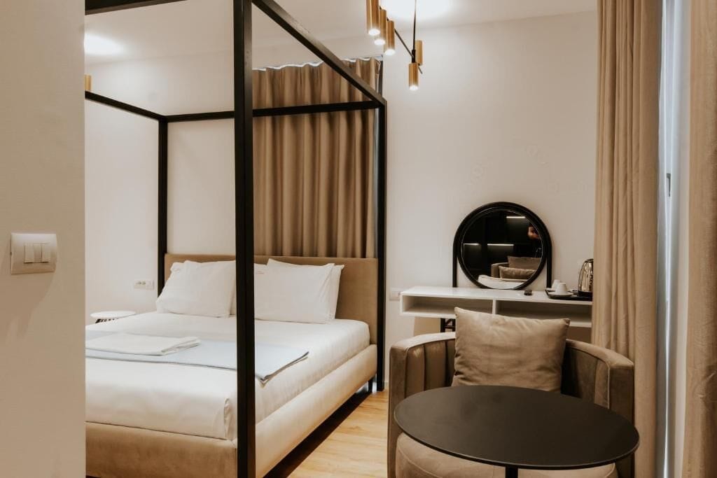 A hotel room with a bed, a desk, a chair, and a round table.
