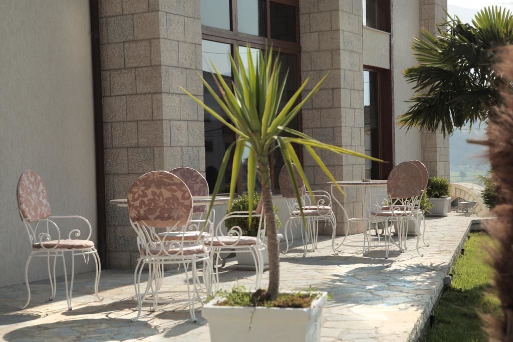 An outdoor seating area with white metal chairs and a central potted plant.