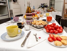 Mesa servida con diversos alimentos, entre ellos tomates, galletas y una botella de aceite de oliva.