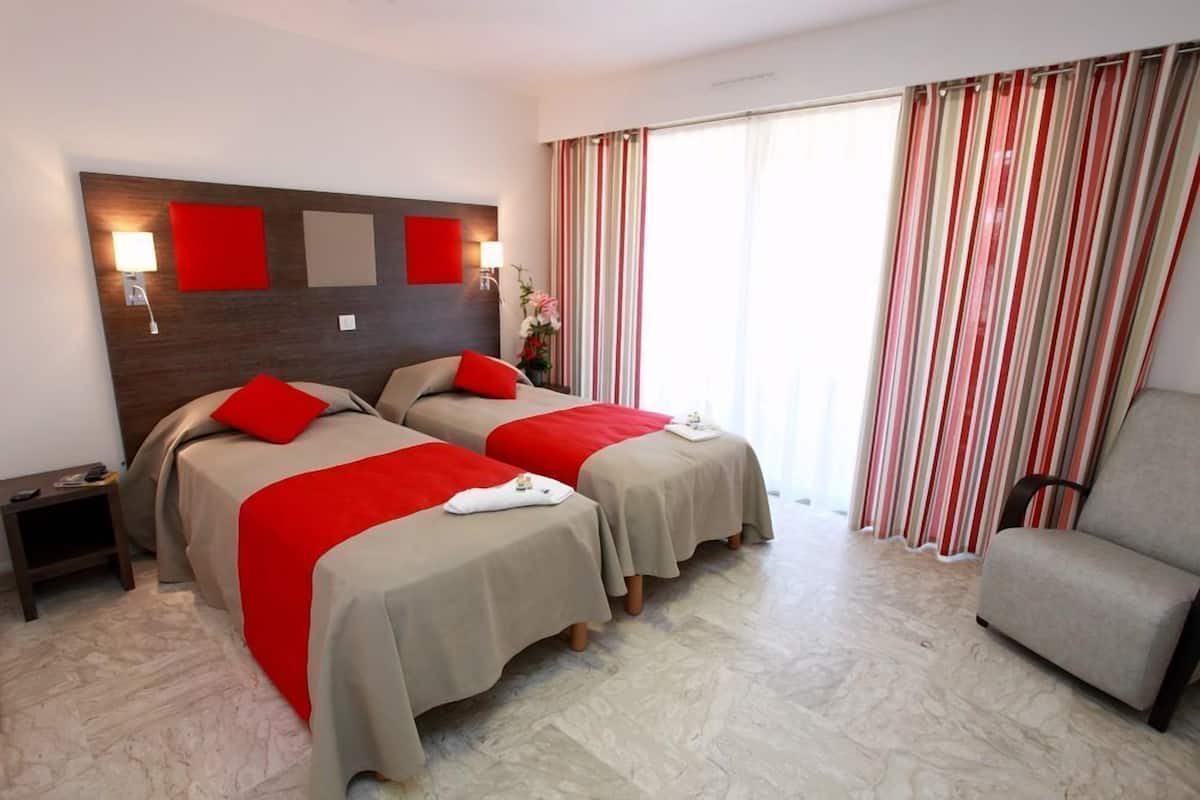 Une chambre d’hôtel avec deux lits, une chaise et une table de chevet.