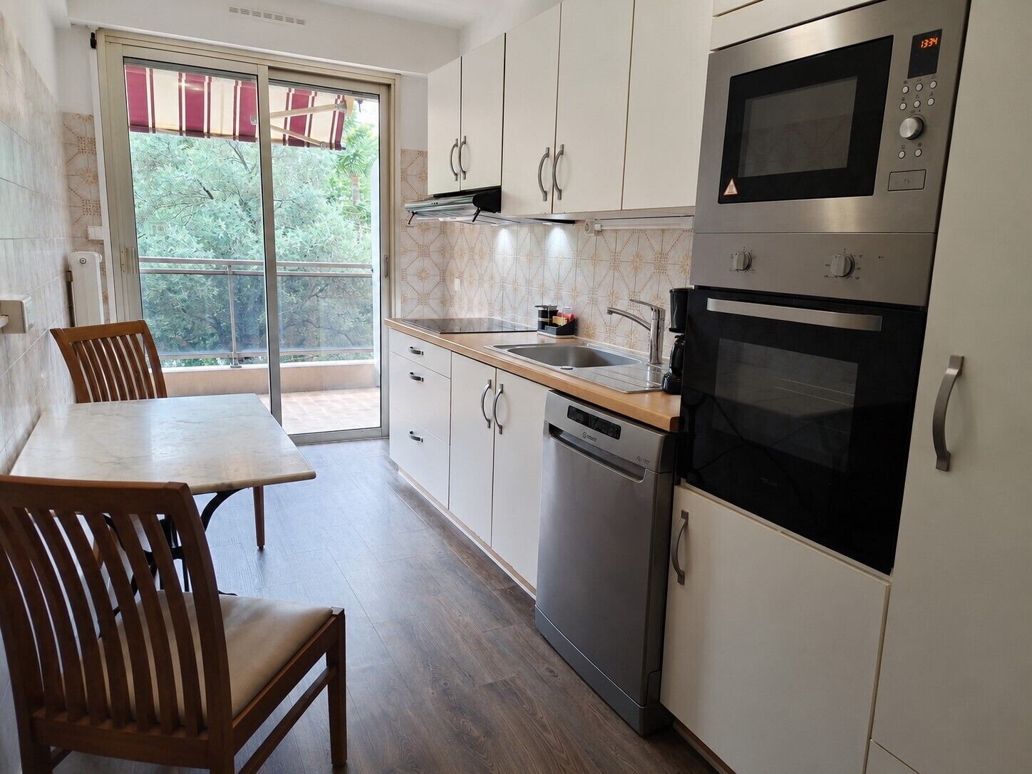 Una cocina moderna con lavavajillas, horno doble y ventana con vistas a zonas verdes.