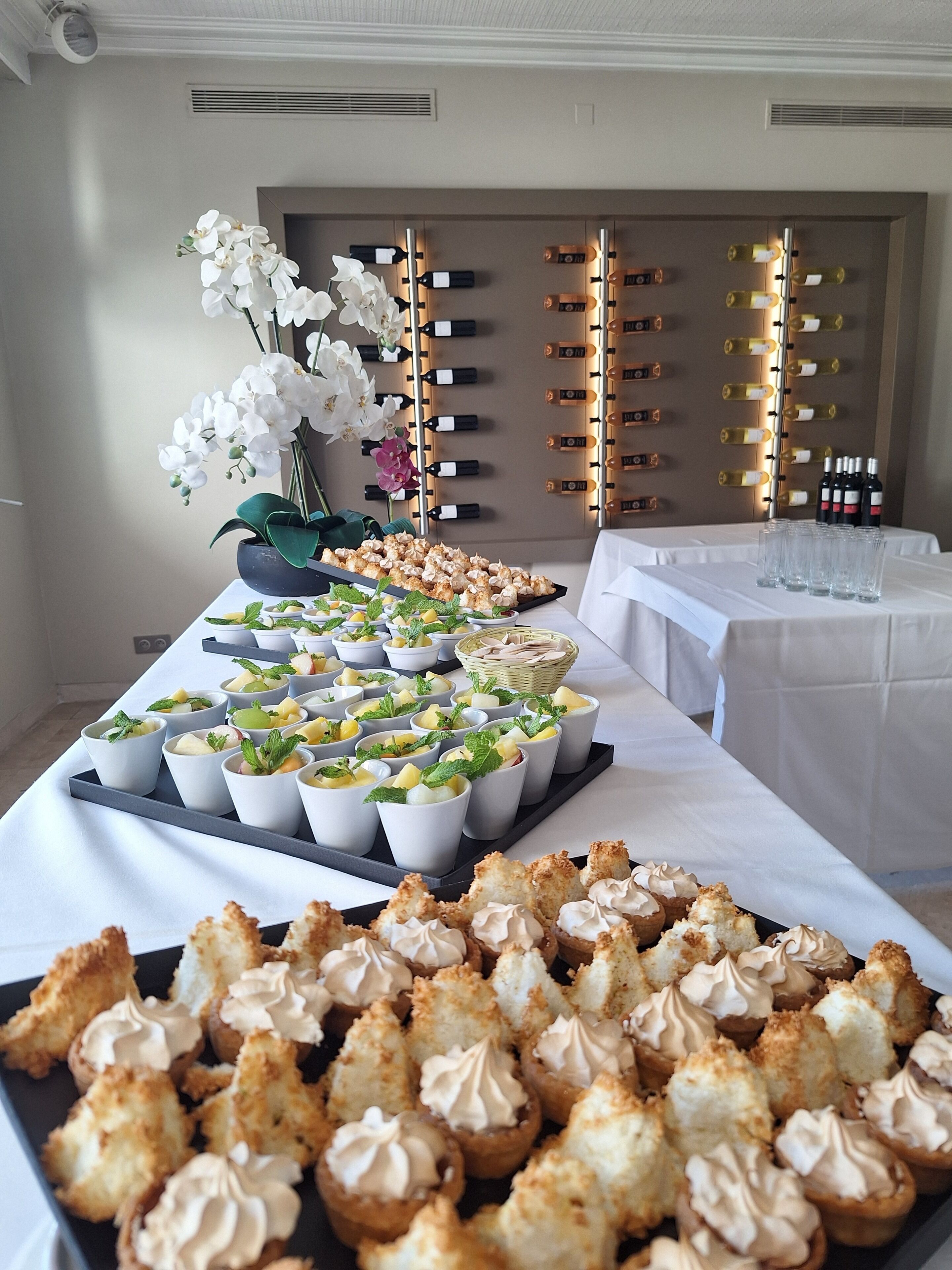 A buffet table with various food items and a wine rack in the background.