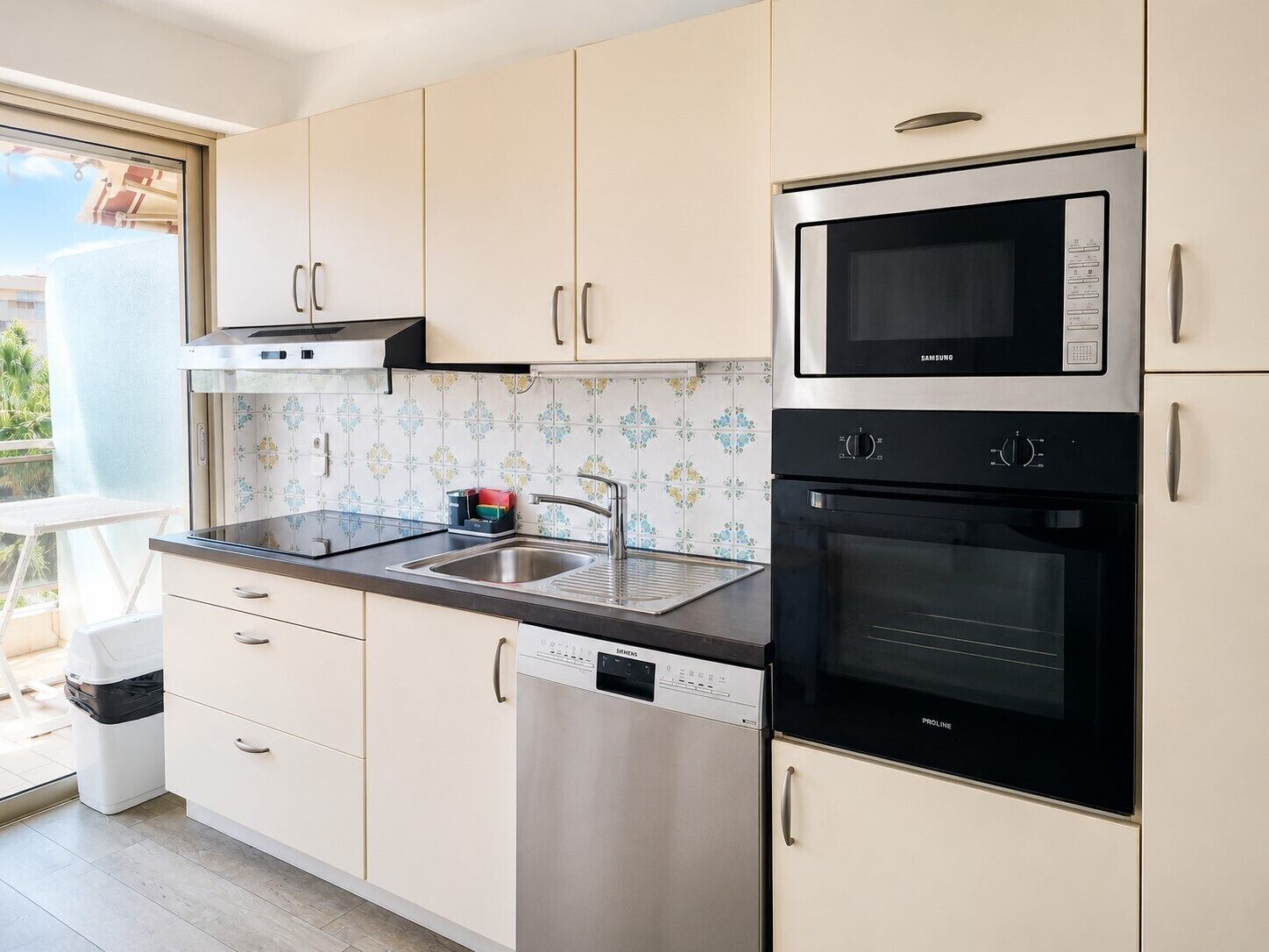 A kitchen with white cabinets, a stainless steel microwave, a dishwasher, and an oven.