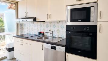 A kitchen with white cabinets, a stainless steel microwave, a dishwasher, and an oven.