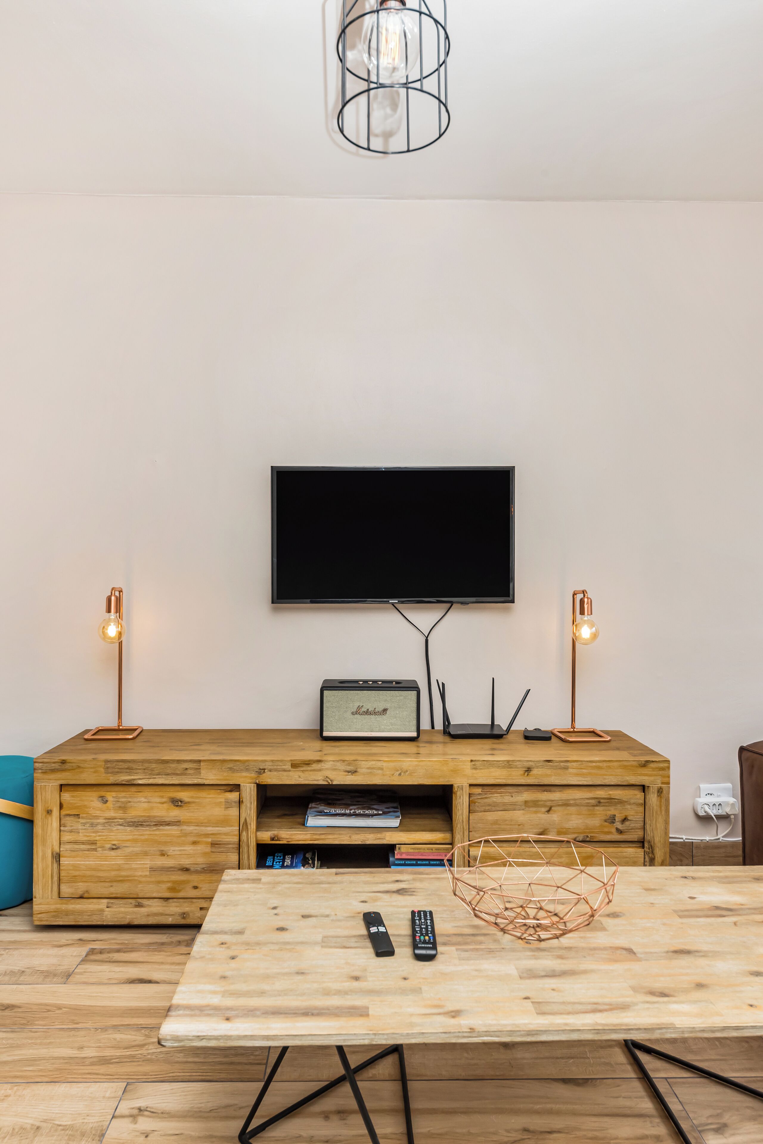 Una sala de estar moderna con un mueble de madera para entretenimiento, un televisor de pantalla plana y una mesa de centro.