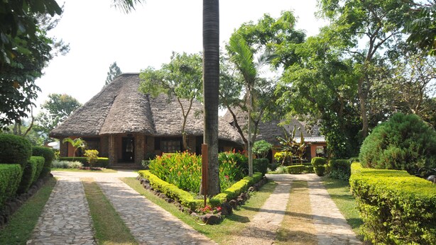 A thatched-roof building surrounded by well-maintained gardens and a stone pathway. - Hotel Kontiki Hoima (Hoima)
