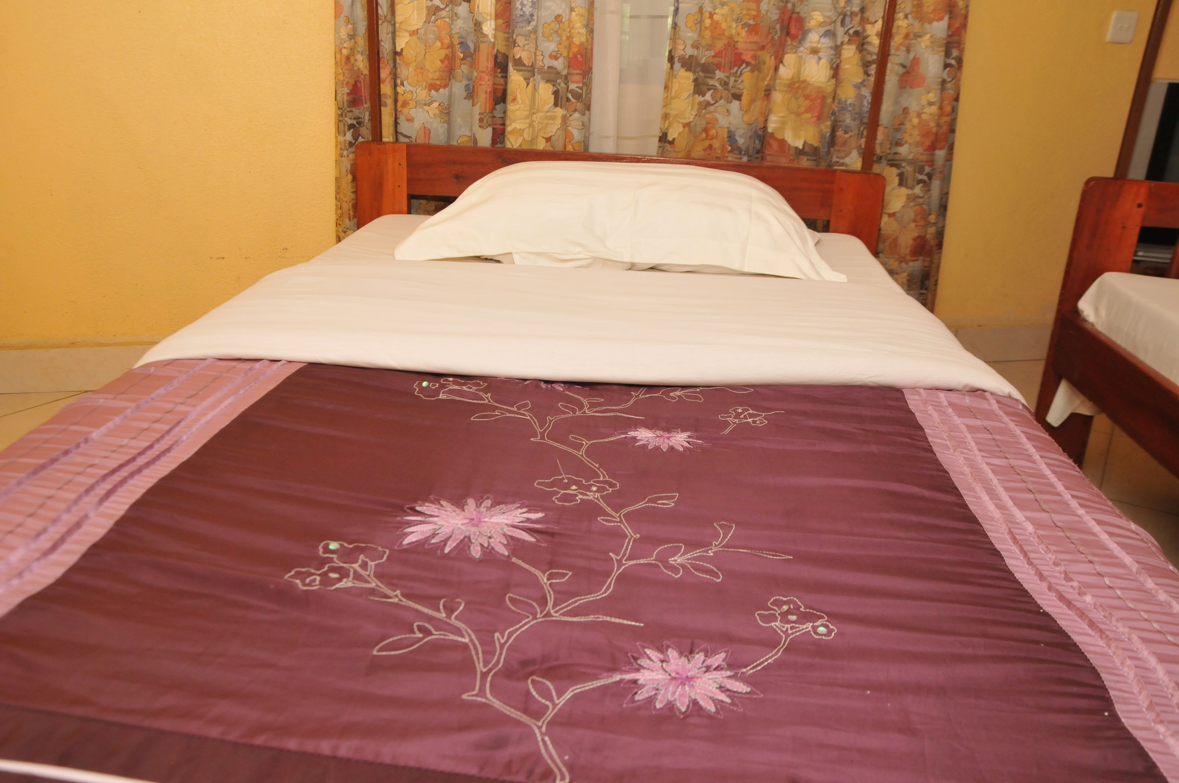 A single bed with a floral-patterned bedspread and a plain white pillow.