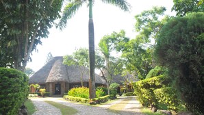 A thatched-roof building surrounded by lush greenery and a well-maintained garden path. - Hotel Kontiki Hoima (Hoima)