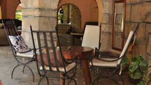 A stone patio with metal chairs and a table, surrounded by arches and potted plants. - Hotel Kontiki Hoima (Hoima)