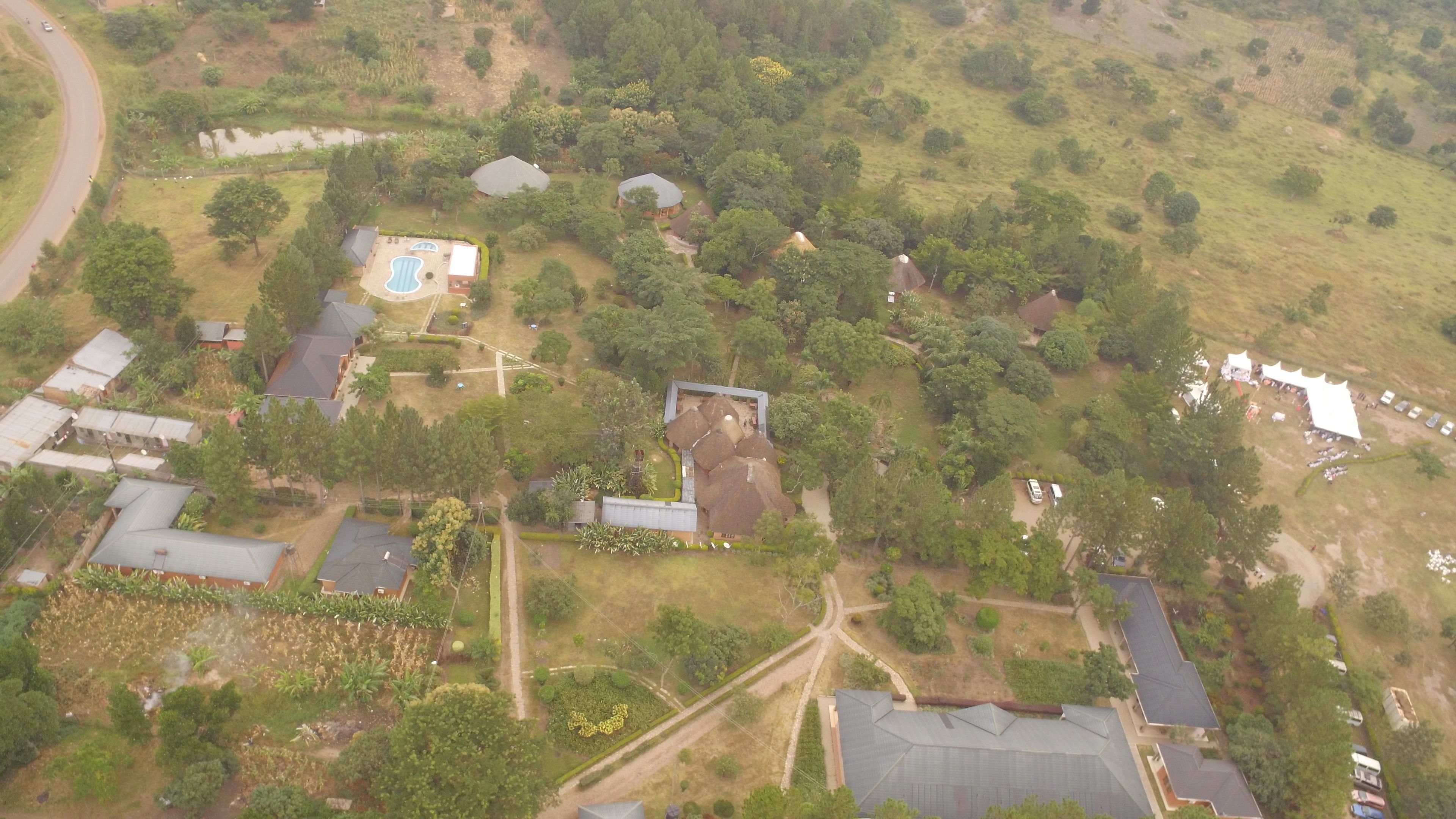 An aerial view of a residential area with multiple houses, a swimming pool, and a large open field.