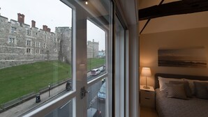 Habitación de hotel con un ventanal que ofrece vistas a un edificio de piedra histórico y un área verde.