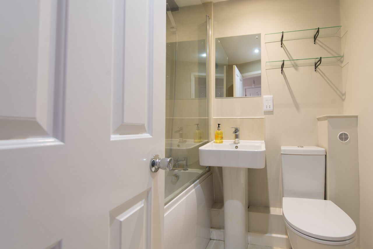 A modern bathroom with a glass shower enclosure, a white sink, and a toilet.