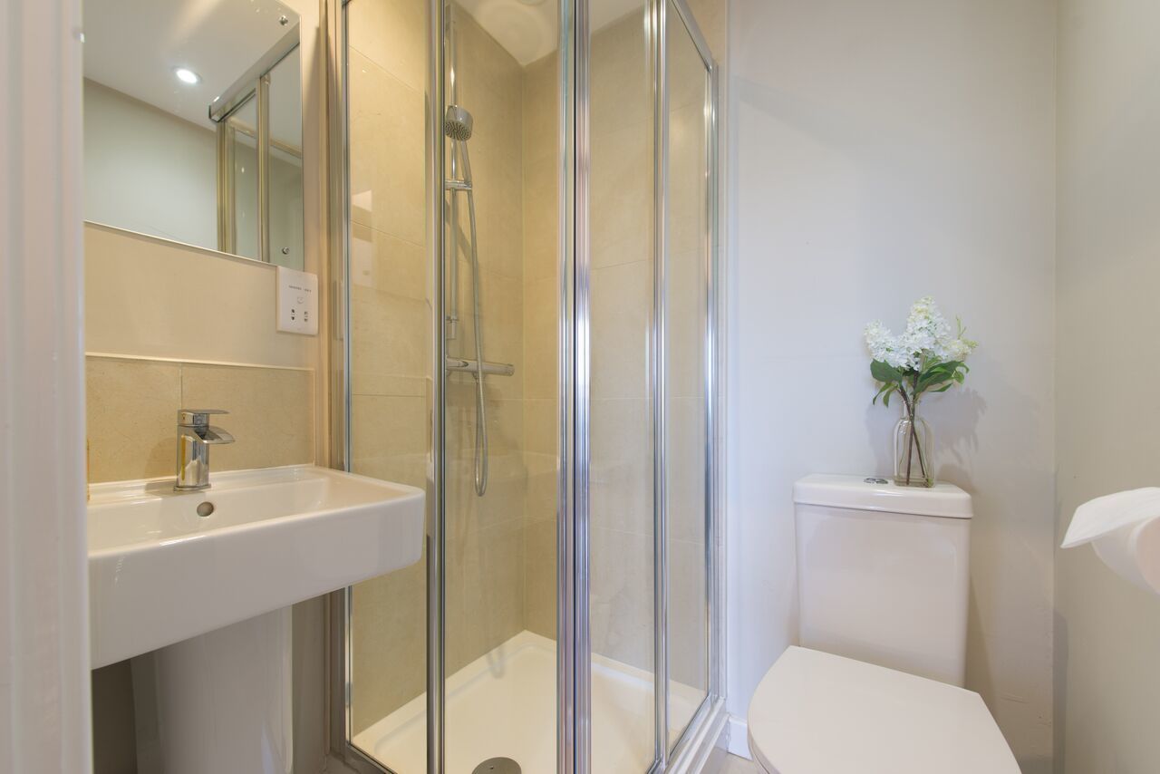 A bathroom with a glass-enclosed shower, a sink, and a toilet.
