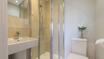 A bathroom with a glass-enclosed shower, a sink, and a toilet.