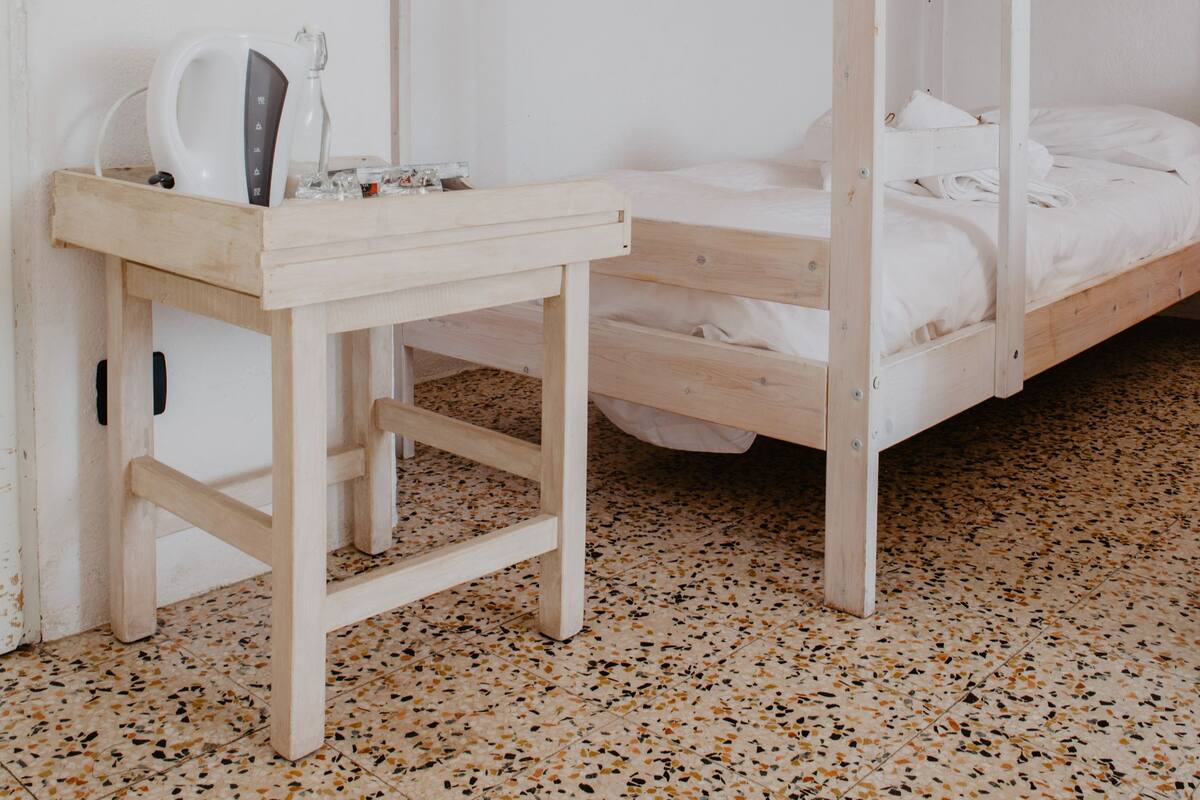 A bunk bed room with a wooden desk and a kettle.