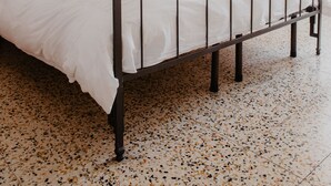 A bed with a metal frame, white bedding, and a wooden door in the background. - Agriturismo Le Piagge (Ponzone)