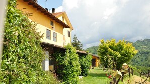 A yellow building with a sloped roof, surrounded by greenery and a clear sky. - Agriturismo Le Piagge (Ponzone)
