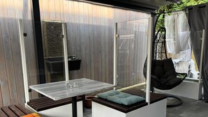 A modern outdoor seating area with a table, cushioned seating, and a hanging chair.
