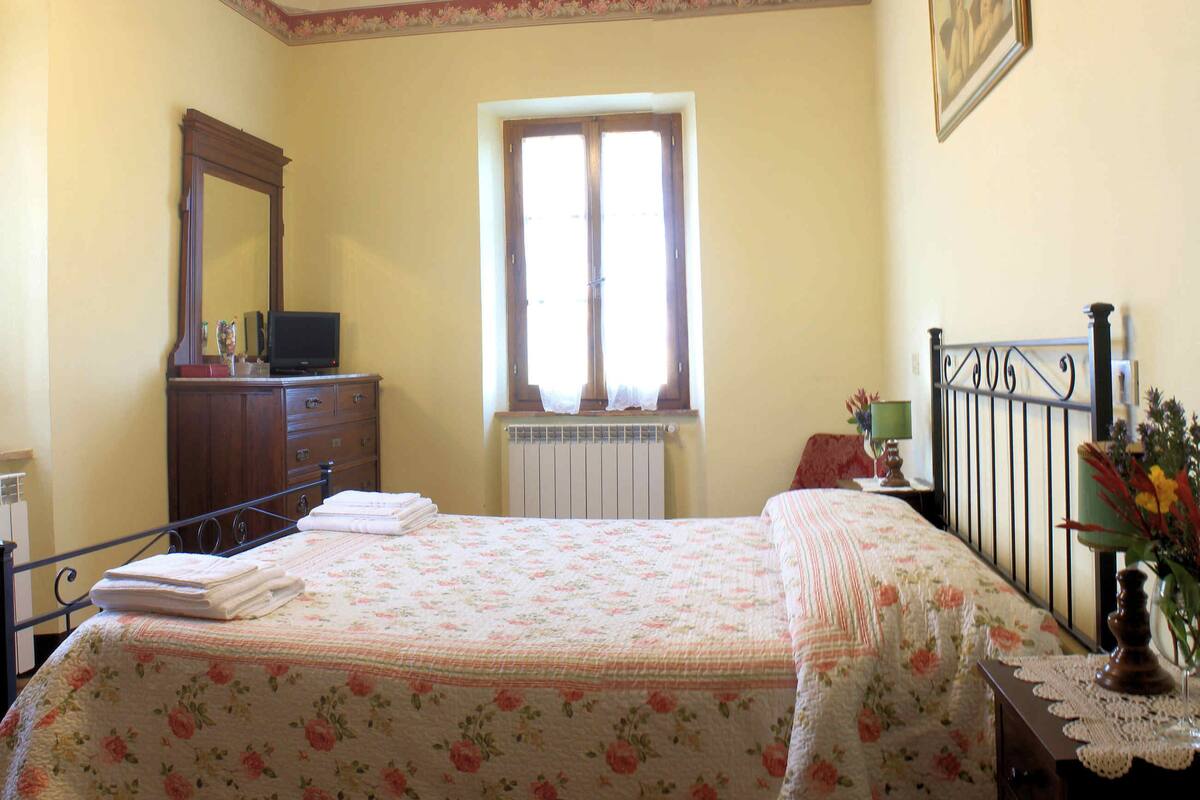 A bedroom with a bed, dresser, mirror, window, and a ceiling fan.