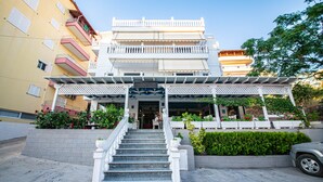 A multi-story hotel with a central staircase leading to a covered entrance. - Hotel Primavera (Sarandë)