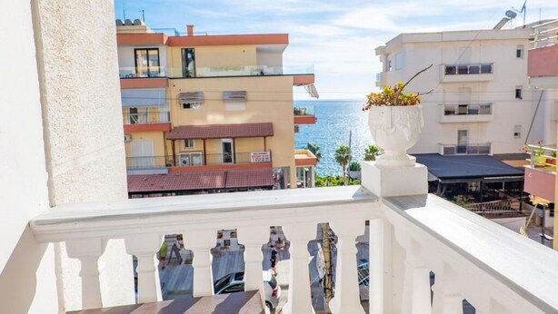A balcony with a view of the sea, a white railing, and a potted plant. - Hotel Primavera (Sarandë)