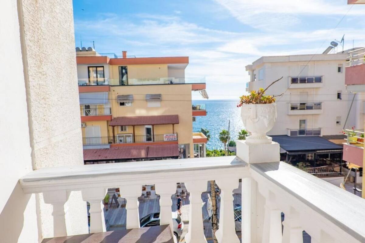 Un balcon donnant sur la mer, avec une balustrade blanche et un pot de fleurs.