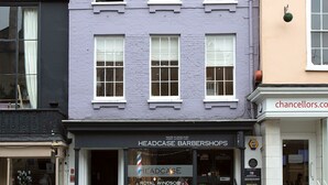 A two-story building with a shop on the ground floor named "Headcase Barbershop." - Hampden Apartments - The George (Windsor)