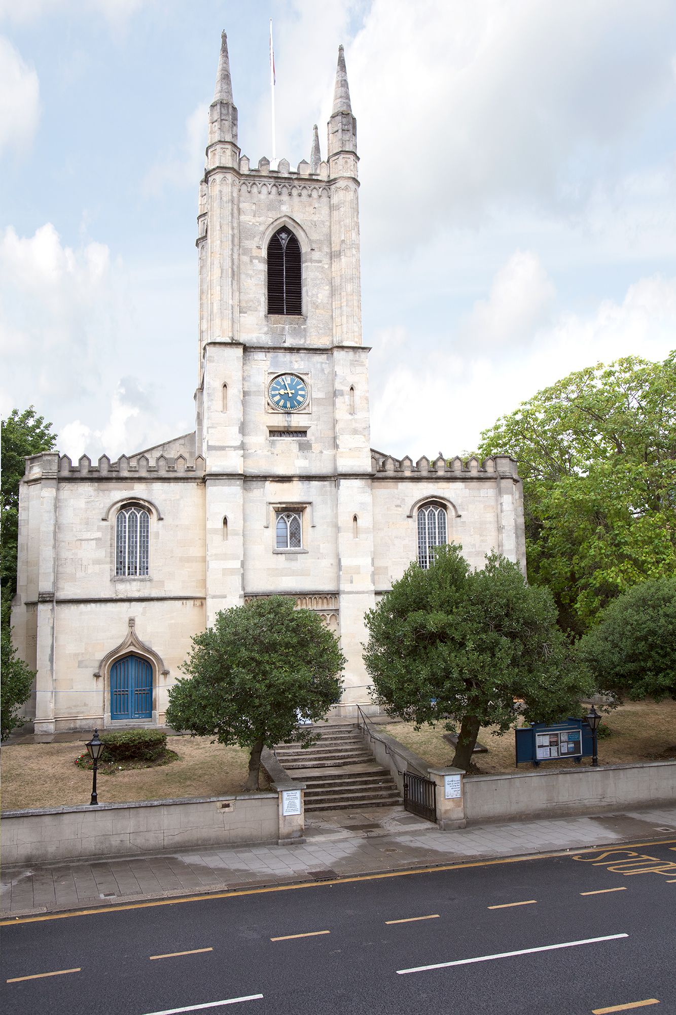 Eine historische Kirche mit einem hohen Turm, einer Uhr und einer blauen Tür.