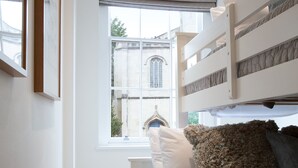 A bedroom with bunk beds, a window with a view of a building, and a framed picture on the wall. - Hampden Apartments - The George (Windsor)
