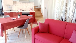 Un espacio habitable compacto con comedor, kitchenette y un sofá rojo.