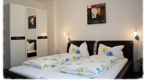 A bedroom with a bed, two bedside tables, a wardrobe, and a wall-mounted artwork. - Höfener Wirtshaus (Monschau)
