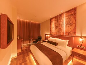 Une chambre d’hôtel avec un grand lit, une œuvre d’art représentant une carte géographique accrochée au mur, un bureau et une chaise.