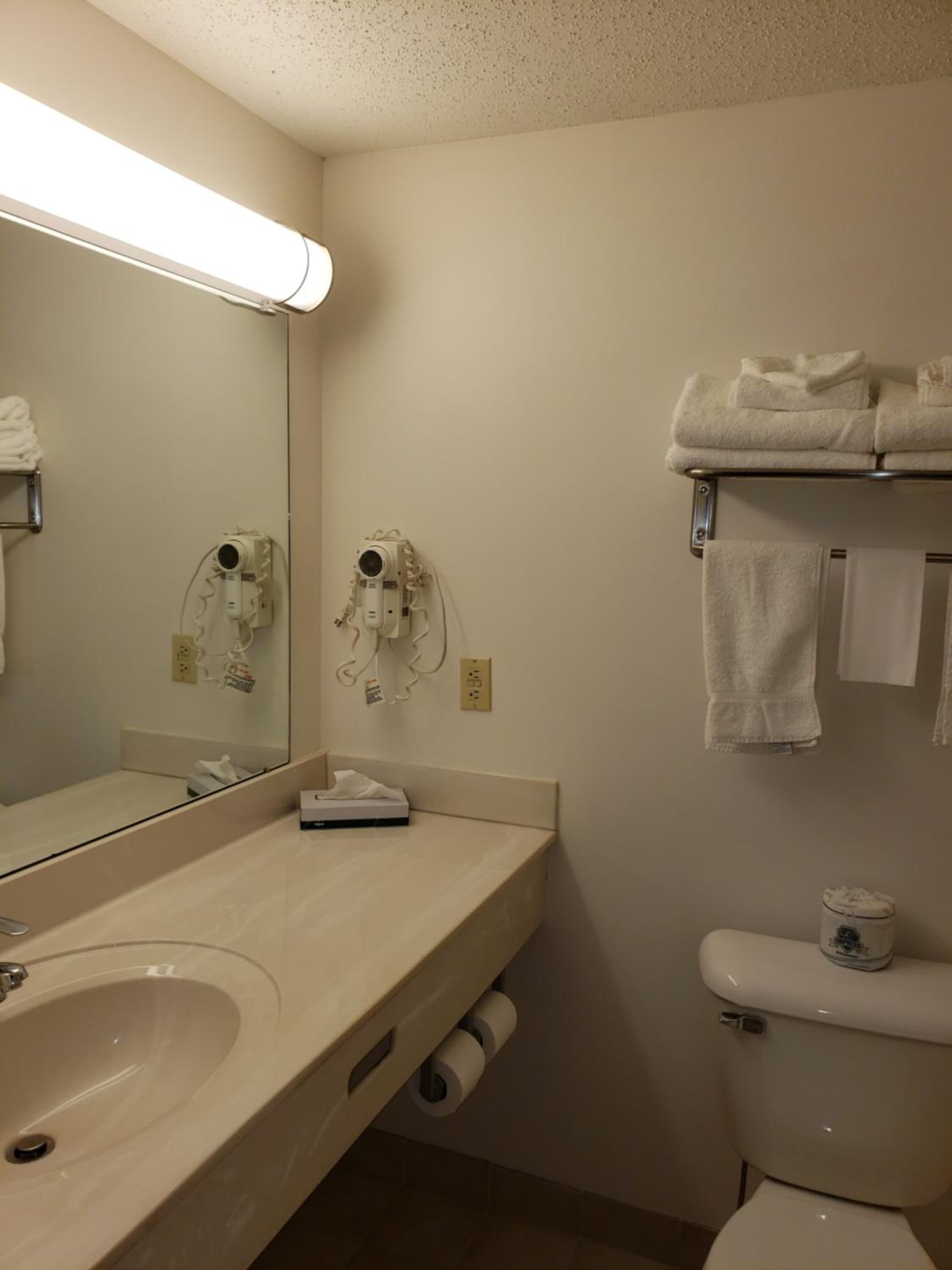 A bathroom with a sink, mirror, towel rack, and toilet.