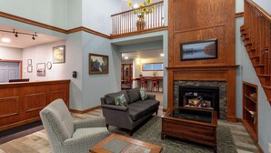 A spacious living area with a fireplace, a sofa, a coffee table, and a staircase. - GrandStay Hotel & Suites Hastings (Hastings)