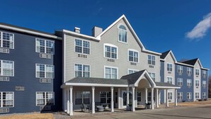 A row of two-story townhouses with a covered front porch and large windows. - GrandStay Hotel & Suites Hastings (Hastings)