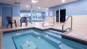 A swimming pool with steps and metal railings, two chairs, and a door. - GrandStay Hotel & Suites Hastings (Hastings)