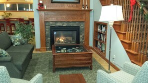 A cozy living room with a fireplace, a coffee table, and a bookshelf. - GrandStay Hotel & Suites Hastings (Hastings)