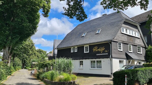 A two-story building with a dark roof and white walls, labeled "Parklife No. 1" indicating it is a guesthouse.