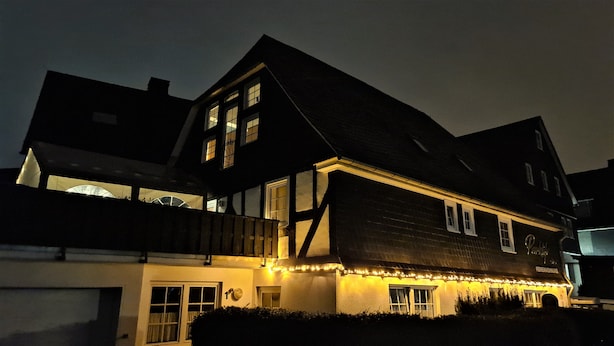 A traditional half-timbered house with a steep gabled roof, illuminated by warm interior lighting. - Parklife Apartments (Winterberg)