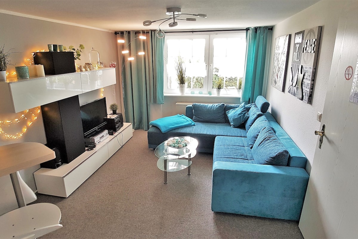 A modern living room with a sofa, a coffee table, a TV on a stand, and a fireplace.