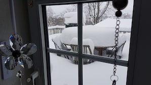A window with a view of a snow-covered outdoor area, including a table and chairs. - Parklife Apartments (Winterberg)