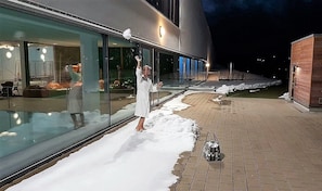 A modern building with large glass windows and a snow-covered ground.