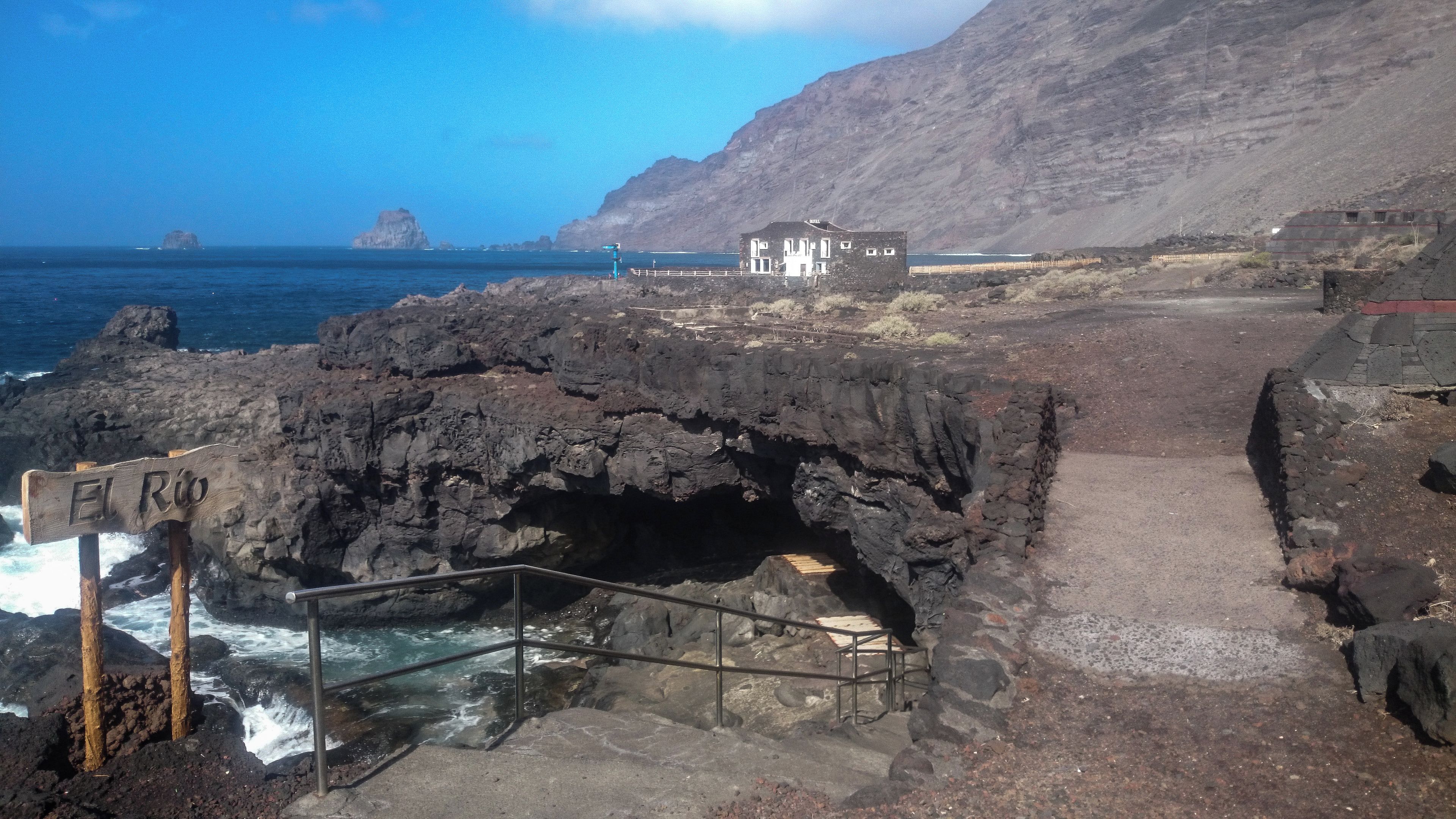 A coastal path leading to a rocky area with a sign reading 'El Río'.