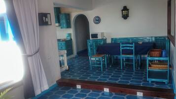 Un comedor con piso de baldosas azules, una mesa con sillas y un reloj en la pared.